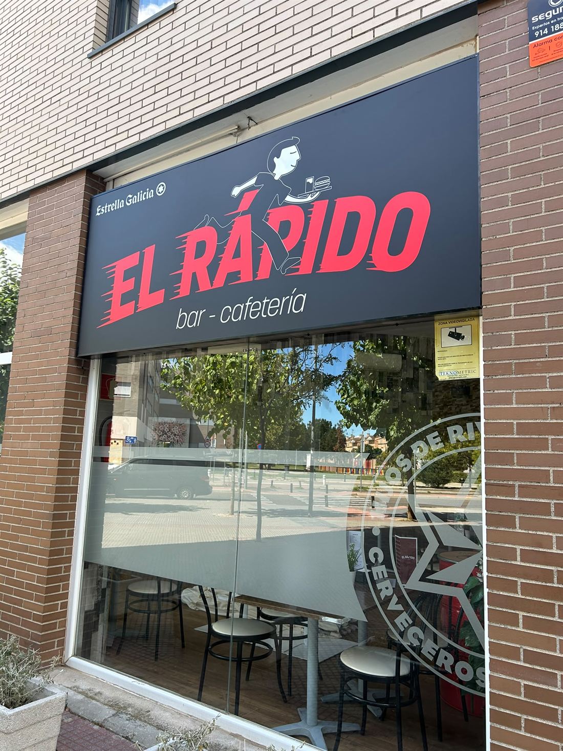 La fachada de El Rápido desde la acera, con el rótulo y la cristalera
